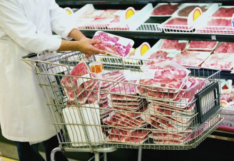 Mid section view of a man putting packaged meat in a shopping cart